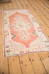 Angled view of a distressed Turkish Oushak runner showing its red and charcoal geometric medallion.