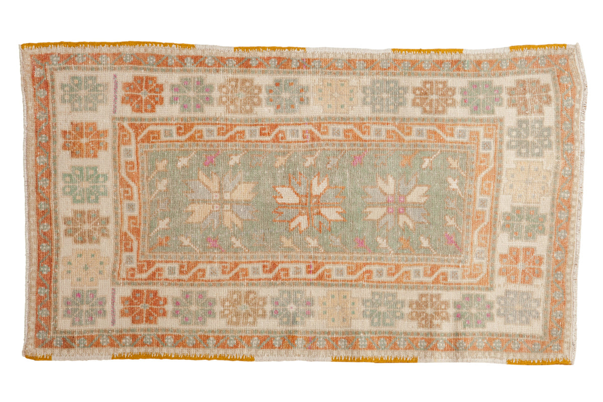 Distressed vintage Oushak rug with starburst medallions in seafoam green, pale rust, and ivory with hints of magenta.