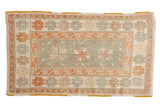 Distressed vintage Oushak rug with starburst medallions in seafoam green, pale rust, and ivory with hints of magenta.