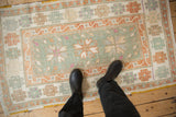 Overhead lifestyle view of a distressed Oushak rug with seafoam, rust, and ivory geometric patterns.