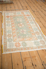 Angled perspective of a vintage Oushak rug showing its seafoam green field and pale rust medallions.
