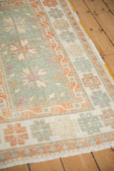 Softly worn texture of a vintage Oushak rug with seafoam, pale rust, and ivory geometric motifs.