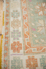 The geometric border in rust and seafoam green with intact saffron side cord on a vintage Oushak rug.