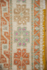 Geometric floral border of a distressed Oushak rug, showing even wear and a saffron yellow side cord.