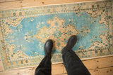 Distressed vintage Oushak runner with sky blue field and sand floral patterns underfoot.