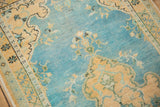 Distressed pile detail with sky blue abrashed field, sand floral motifs, and visible wear.
