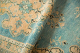 Distressed vintage Oushak rug texture detail with sky blue and sand floral motifs.
