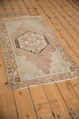 Distressed Oushak rug corner showcasing faded mauve, pale green spandrels, and worn texture.