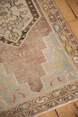 Distressed Oushak rug corner with faint foundation, dusty mauve, pale blue, and sage.