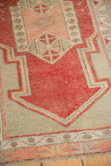 Detailed view of the even wear on the Oushak's geometric prayer motif in cherry red and greige.