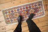 Distressed Oushak mat runner, colorful floral and pinwheel motifs in aubergine, ivory, gold, tangerine.