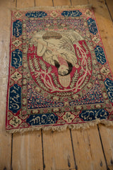 A collector's pictorial Kerman rug seen from an angle, showing the royal figure and inscription border.