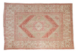 Vintage distressed Oushak carpet with a diamond medallion in dusty burgundy and pink on an ivory field.