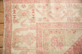 Wide-banded border and corner spandrel of a distressed Turkish Oushak in pink and ivory hues.
