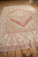 Low-angle view of a distressed Oushak's wide border with cloudband motifs and pink abrash.