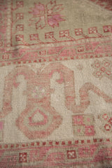 Dusty burgundy cloudband motif on the worn, hand-knotted ivory pile of a vintage carpet.