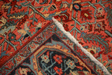Folded corner of a vintage Heriz rug showing the hand-knotted construction, back, and fringe.