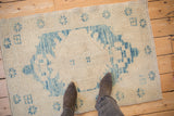 Distressed Oushak rug's faded sky blue medallion and abrashed ivory pile.