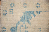 Distressed Turkish Oushak rug's hand-knotted pile, with even wear and sky blue motifs on ivory.