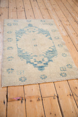 Distressed Oushak rug pile texture with worn sky blue geometric patterns on ivory.