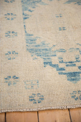 Distressed Oushak rug texture: sky blue patterns on abrashed ivory, with intact selvage.