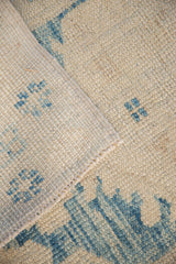 Hand-knotted Oushak rug: distressed sky blue motifs on ivory pile and woven foundation.