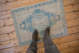 A distressed Oushak rug with sky blue and ivory tones viewed from above to show scale.