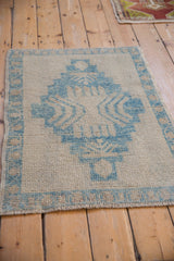 Angled view of a distressed Oushak rug with a sky blue geometric medallion.