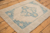 Evenly worn, hand-knotted pile on the corner of a distressed ivory and blue Oushak rug.