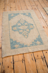 Angled view of the hand-knotted distressed Oushak rug in ivory and dusty denim blue.