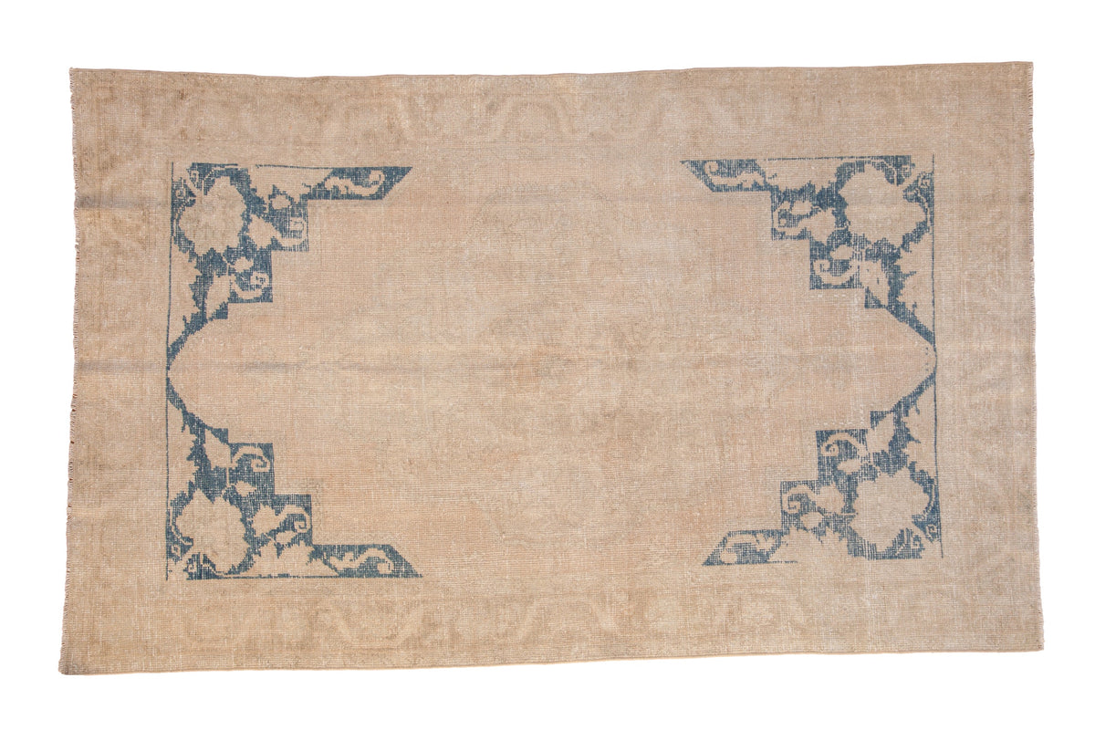 Vintage distressed Oushak carpet with a low-pile beige field and bold cobalt blue corner spandrels.