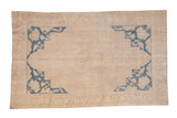 Vintage distressed Oushak carpet with a low-pile beige field and bold cobalt blue corner spandrels.