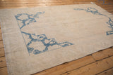 Distressed low-pile texture and cobalt blue corner spandrel on a vintage ivory Oushak carpet.