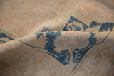 A soft fold revealing the distressed, low pile texture of a vintage Turkish Oushak carpet.