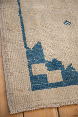 Distressed ivory pile texture with a serrated cobalt blue geometric pattern and intact side selvage.