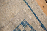 Distressed Oushak rug runner's antique ivory pile, visible even wear, and indigo blue woven foundation.