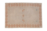 Distressed Oushak rug with a pale copper floral border on a worn antique ivory field.