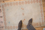 View from above a distressed Oushak rug, with feet for scale on the ivory pile.