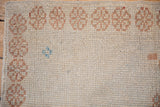 Textured, worn pile of an ivory Oushak rug with a pale copper-gold geometric border.