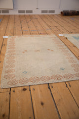 Angled view of the distressed Turkish Oushak rug showing its even wear and low pile.