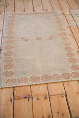 Close-up of the hand-knotted texture and copper-gold border on a vintage distressed Oushak rug.