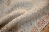 Close-up of the distressed Oushak rug's even wear and nubby, hand-knotted texture.