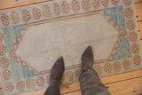 Distressed Oushak rug with floral border and blue abrashes in corner spandrel.