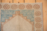 Floral top border and powder blue spandrel of a distressed Oushak rug corner.