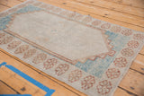 Distressed Oushak rug border: repeating floral pattern in muted brown and powder blue.