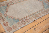 Distressed Oushak rug corner detail, highlighting worn pile, pale floral border, and blue tones.