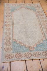 Distressed Oushak rug corner showing floral border and pale blue stepped lozenge outline.