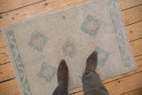 Distressed vintage Oushak rug's even wear, faint foundation, ivory, and powder blue diamond medallions.