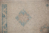 Distressed ivory Oushak rug pile, showing wear and powder blue diamond motif.