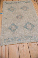 Distressed ivory and powder blue Oushak rug with diamond motifs, showing even pile wear and selvage.